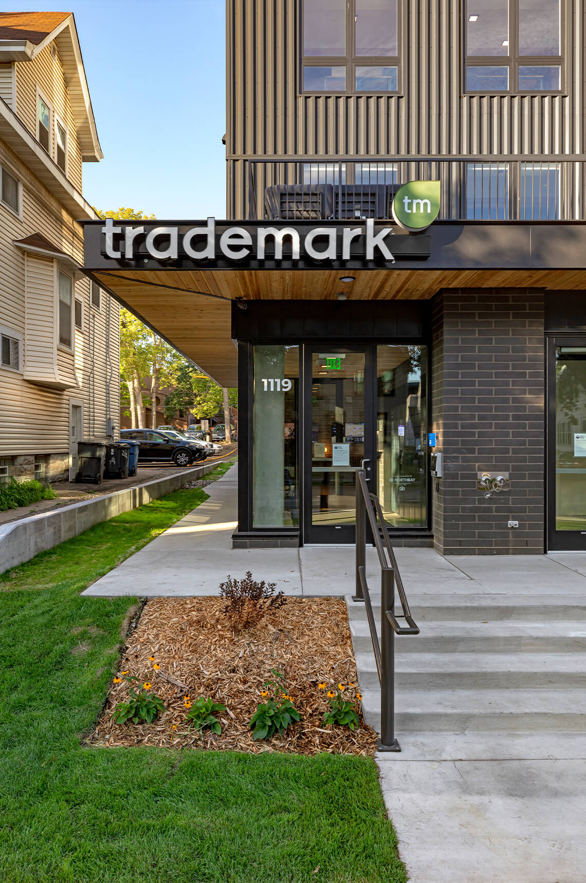 Modern apartment building entrance with 'trademark' sign.